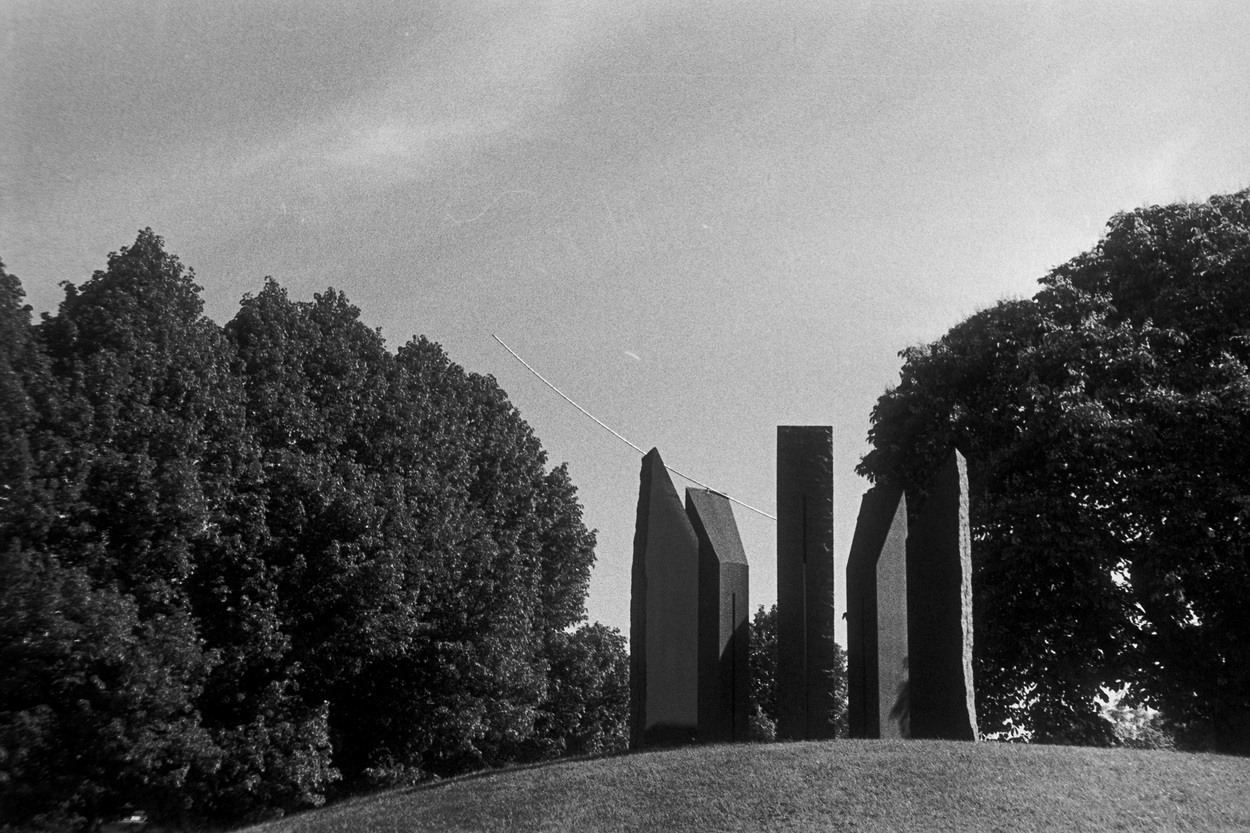 A photo of a stone formation with a metal arc in the sun